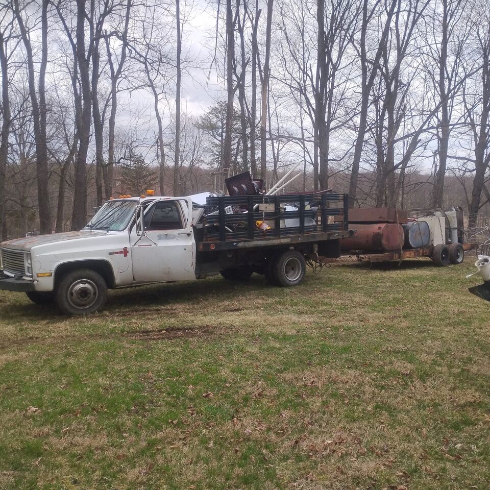 White BuccaneerSalvage flatbed truck hitched to a trailer, ready for a paid junk removal job