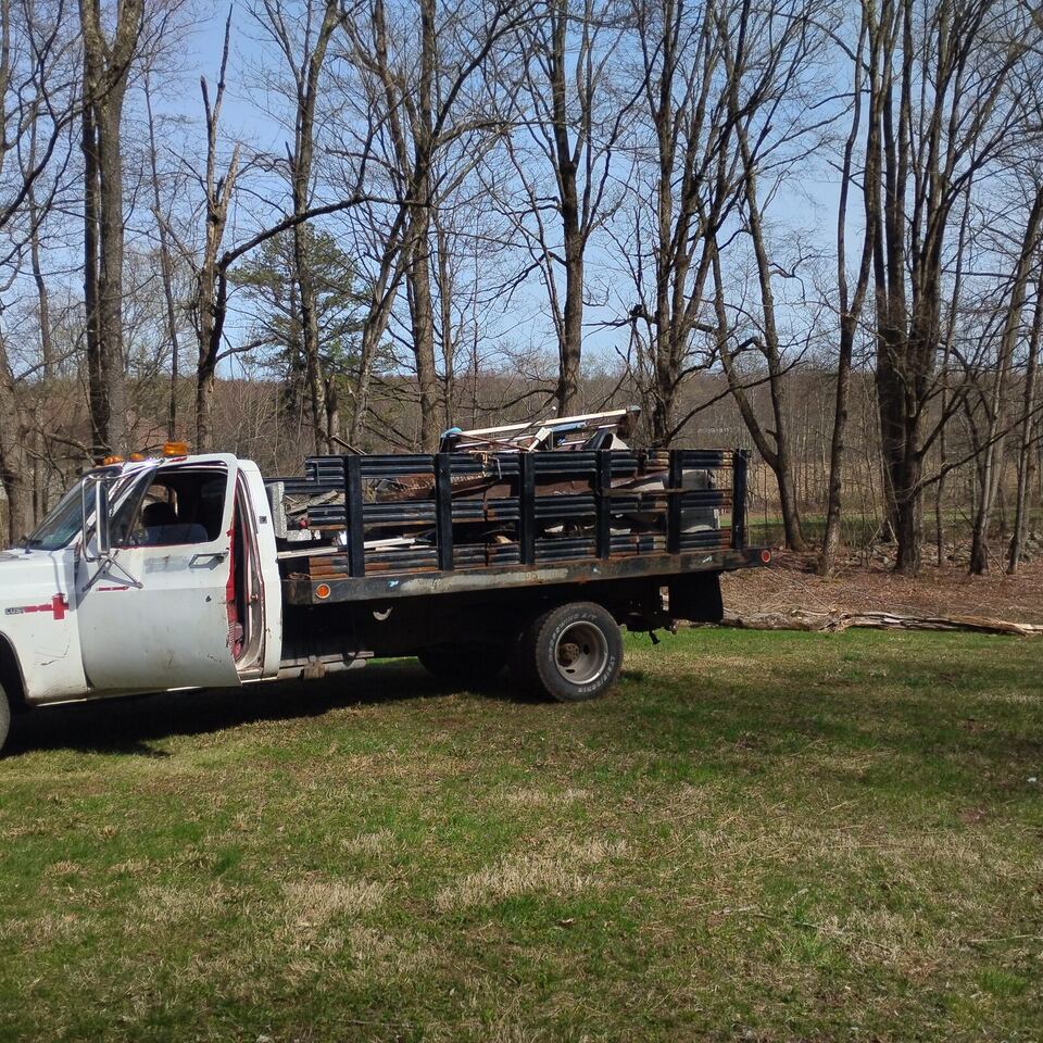 BuccaneerSalvage white flatbed truck loaded with scrap metal and appliances for a local haul